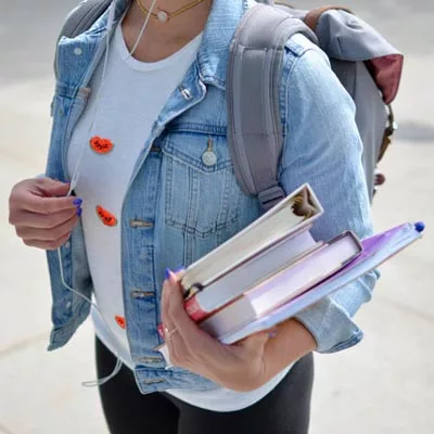 Foto eines Mädchens mit Büchern und Rucksack